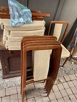 Stacked teak chair frames, bag of hardware, seat pads