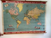 Full view of the roll-up world map on wall showing advertising banners and wooden slats