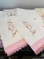 Group of towels showing floral monogram set with pink crochet lace hem