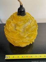 Front view of yellow lucite ribbon globe pendant with ruler for scale