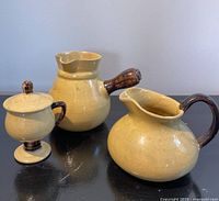 Front view of three yellow stoneware pieces on black surface