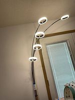 Lamp illuminated showing five ring light heads on curved arms