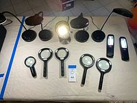Top view showing all items: four desk lamps, six magnifiers, two work lights