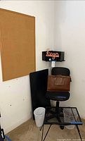 Group shot showing chair, corkboard, panel shelf, briefcase on chair, keys sign, file sorter, wastebasket, side table