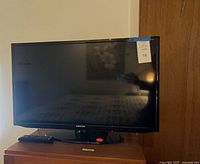 Front view of Samsung 32" TV on stand with remote visible