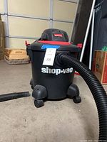 Front view of Shop-Vac vacuum with attached hose and visible casters