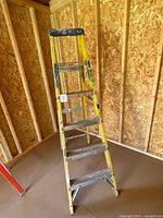 Full view of yellow 6 ft Louisville ladder in shed