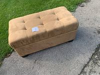 Full view of beige upholstered storage ottoman on driveway