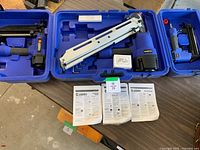 Overview of three Campbell Hausfeld nailers in open cases with manuals and nail boxes on table