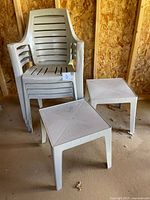 Stack of four beige plastic chairs with two square side tables
