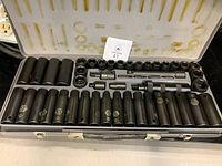 Opened metal case showing complete set of deep and shallow impact sockets, extensions and joint