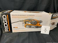 Front of original box showing RIDGID R27401 belt sander image and specs