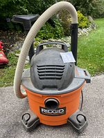 Full view of Ridgid orange wet/dry shop vacuum with hose and wand