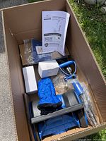 Contents of box showing snow shovel parts, accessories and manual