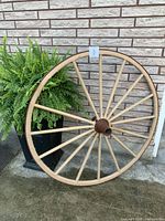 Full view of wagon wheel leaning against brick wall