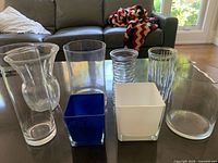 Front view of seven glass vases and planters on table