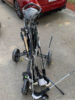 Push cart standing upright with collection of golf clubs loaded