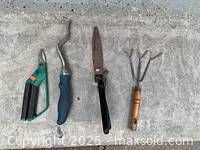 Four hand garden tools on concrete surface