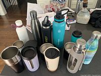 Overall view of assorted bottles, tumblers and travel mugs on countertop