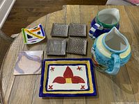 Ceramic pitchers, platter, coasters, plate and tile displayed on table