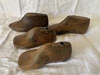 Group of four small wooden shoe lasts for children's shoes on white cloth