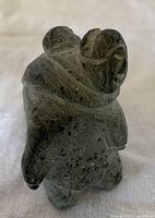 Rear view of soapstone carving showing mother figure with baby in hood