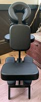 Front view of black portable massage chair showing headrest, chest pad, seat and leg pads
