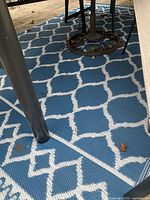 Blue and white lattice outdoor rug beneath patio furniture