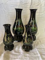 Four black lacquer vases with carved wood stands, two tall two shorter