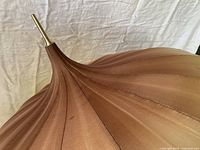 Close-up of parasol tip showing silk fabric ribs and brass finial