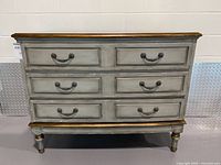 Front view showing three drawers, hardware, legs