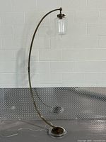 Full view of gold curved floor lamp against wall