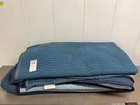 Two folded blue quilted moving blankets on table