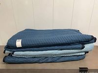 Stack of folded moving blankets showing quilted pattern