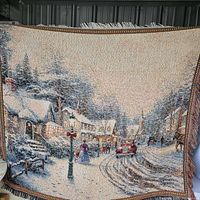 Full view of woven tapestry showing entire winter village scene and fringed edges