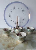 Overview of platter on stand with four teacups and creamer