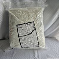 Factory-sealed package of cream plush area rug