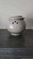 Front view of round speckled stoneware butter jar with vent holes