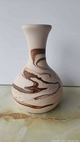 Front view of beige-tan stoneware bud vase with brown swirl marbling and flared rim