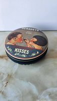 Angled view showing side and lid artwork of the Hershey’s Kisses tin