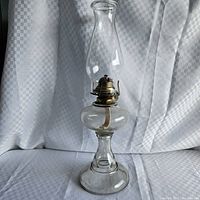 Full view of clear glass oil lamp with chimney