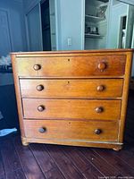 Front view showing four drawers, knobs, keyholes, wooden construction