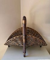 Side view showing woven wicker body and upright handle support