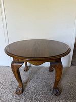 Full view of table front showing circular top, four legs, claw feet