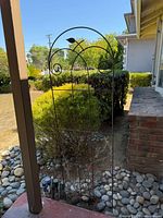 Full view of arched wrought-iron garden trellis installed in ground