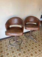 Two brown mid-century swivel bar stools front view