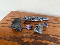 All five mineral specimens displayed on wooden surface: obsidian, fulgurite, galena, two amethysts