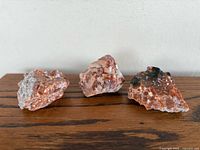 Three rough red and white mineral rocks on wood surface