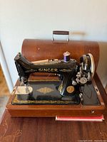 Full view of Singer sewing machine on wooden base with cover behind
