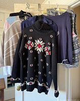Group of five sweaters hanging on door